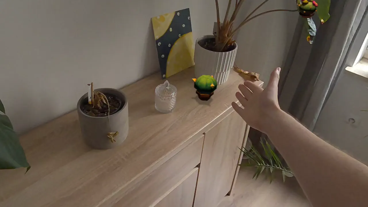 A hand placing a small potted cactus on a real dresser